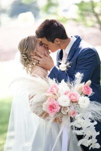 pink and white floral bouquet with wedding couple