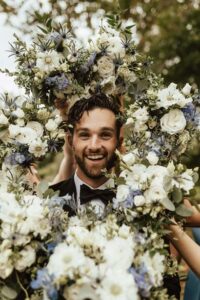 groom surrounded by floral bouquet